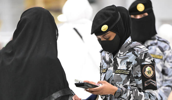 Saudi security forces officer using a handheld biometric device for visa verification at a Hajj checkpoint