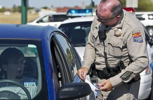 Highway patrol officer at a traffic stop, reviewing a driver’s license at the vehicle window
